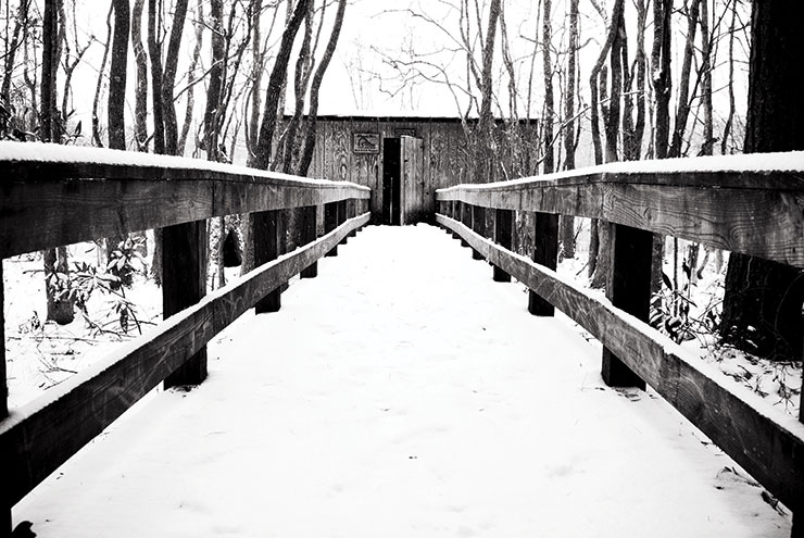 Snow covers a wooden walkway and house.