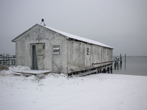 Snow covers a building near a pier.