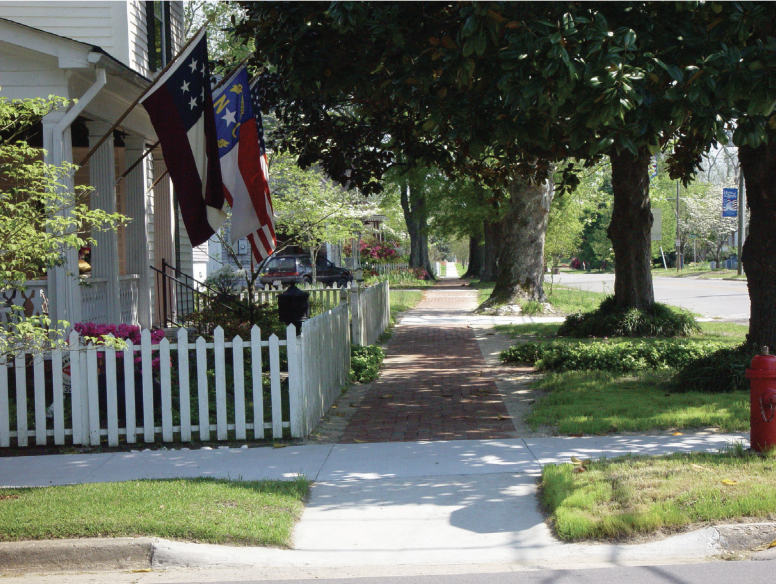 A sidewalk with houses to the left