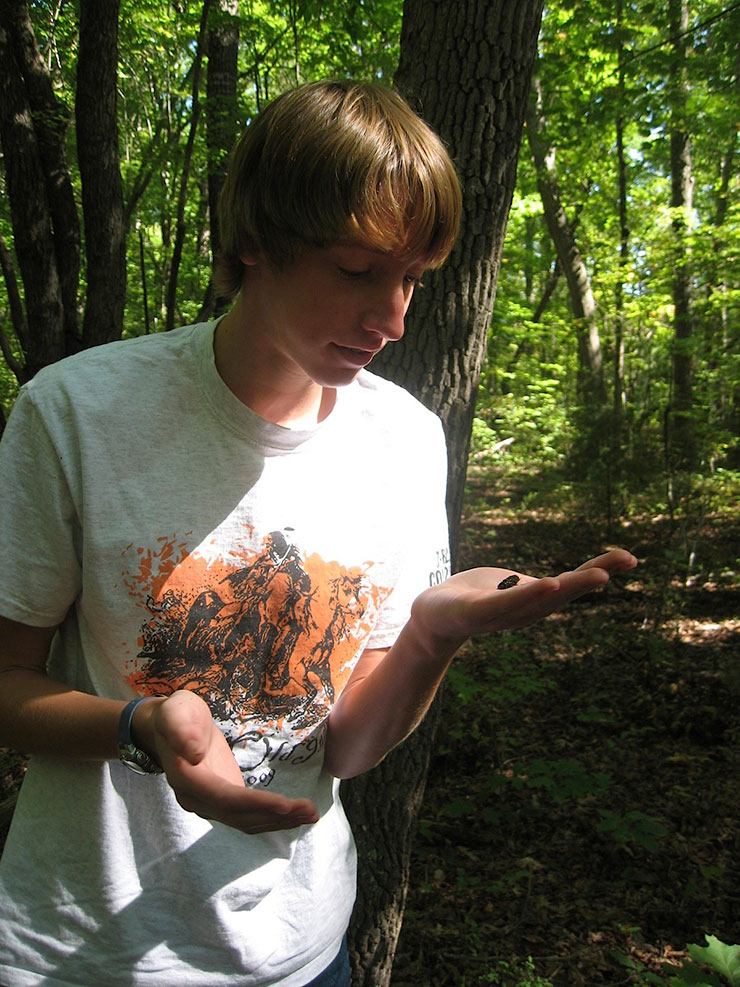 Male student observes nature outside.