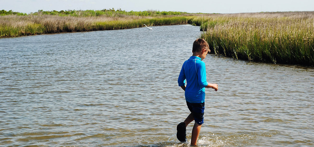 Child walking on marsh bank