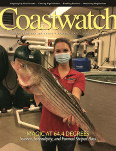 image: cover of the 2021 Spring Issue, researcher holds a striped bass