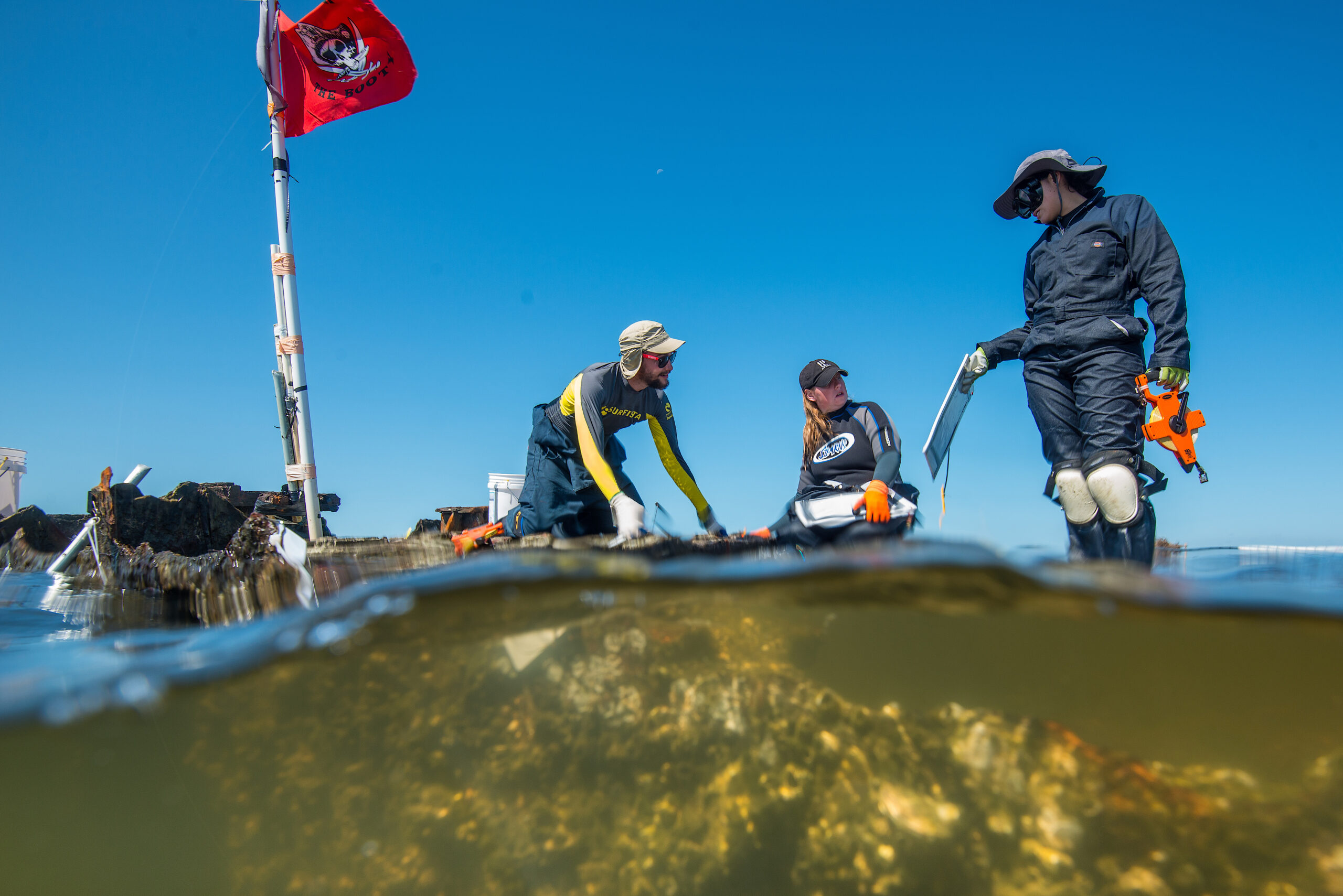 image: researchers at work on a partially submerged shipwreck.