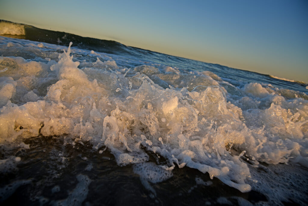 image: A wave splashing on a beach.