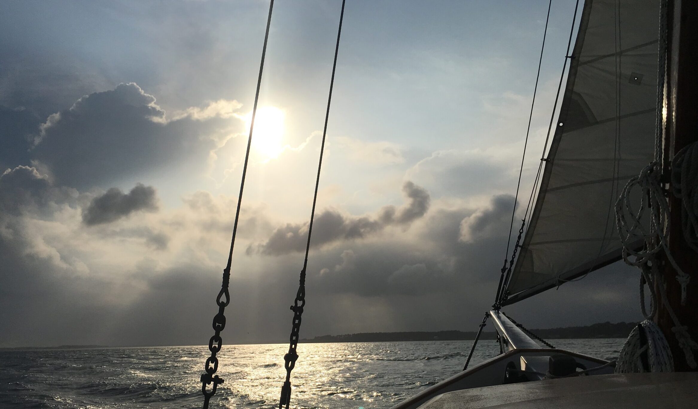 image: bow of a sailboat heads towards a cloudy horizon.
