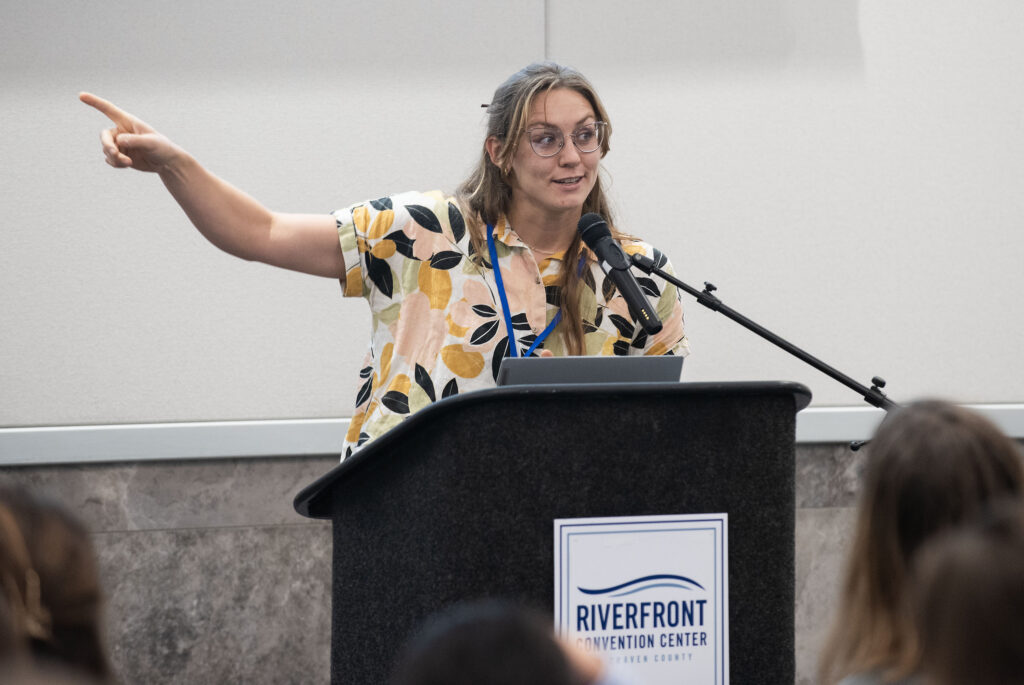 image: Eve Eisemann, UNC-CH, talks about the evolution of oyster reefs during the afternoon research presentations at the 2024 North Carolina Coastal Conference.