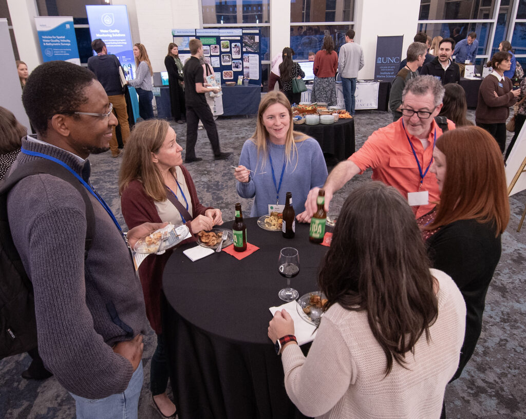 image: Participants take the opportunity to network during the evening reception at the 2024 North Carolina Coastal Conference. The event, hosted by North Carolina Sea Grant, was held Nov. 13-14, 2024 at the Riverfront Convention Center in New Bern, N.C. (Photo by Jamie Moncrief).