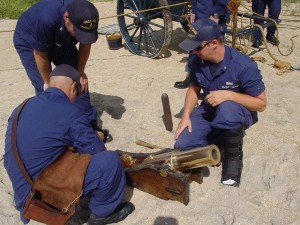 Crew members and the keeper prepare the Lyle gun that fires a 20-pound shot, seen protruding from the sand.