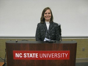 Susan White stands at podium with NC State University logo.