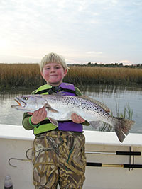 Boy in life jacket holding fish 