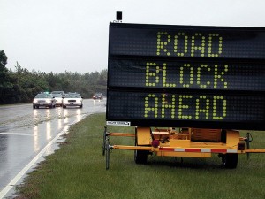 A road block sign near a flooded road.