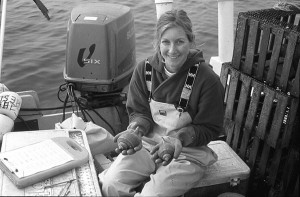 Elaine sits on a boat and measures whelk.