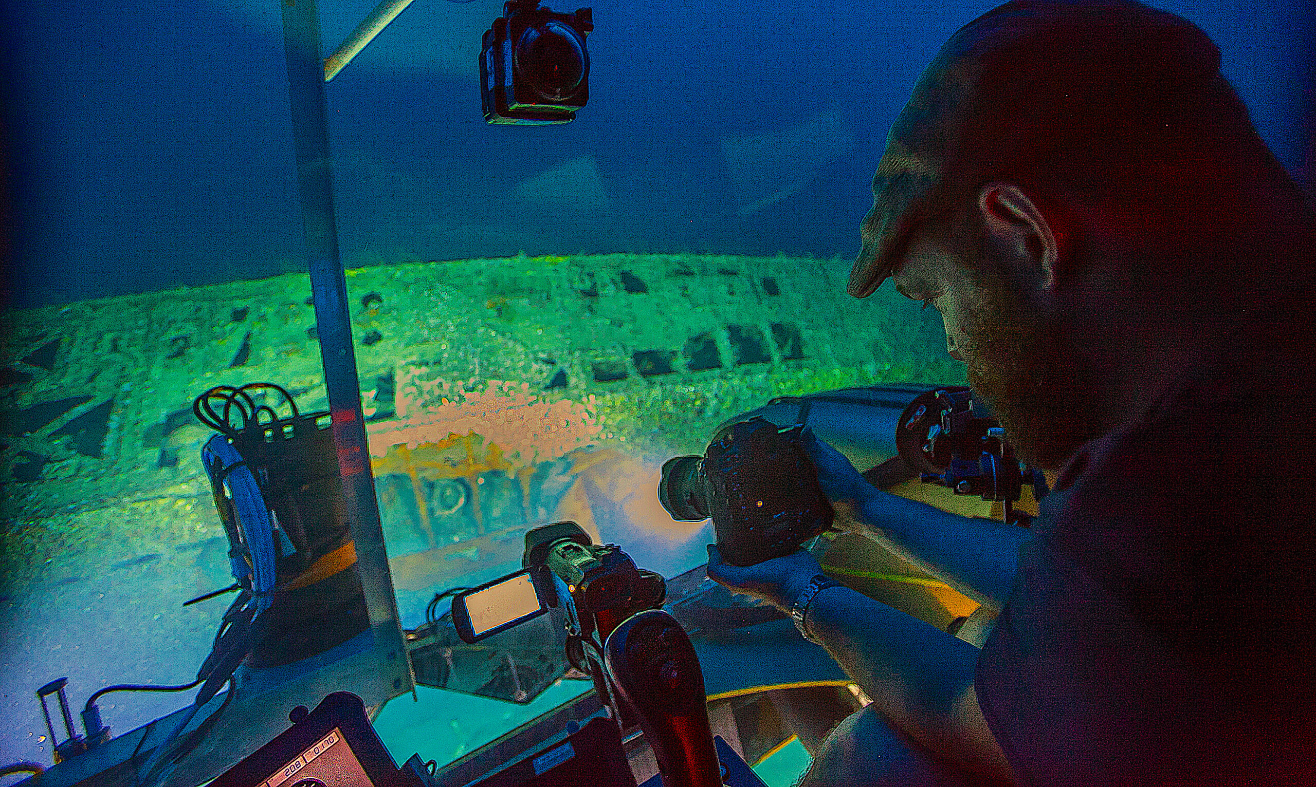 image: Joe Hoyt, maritime archaeologist with the NOAA Office of National Marine Sanctuaries, takes photos of the shipwreck from the submersible. Credit: Robert Carmichael/NOAA’s Battle of the Atlantic Expedition.