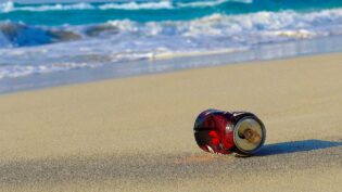 image: coke can on the beach.