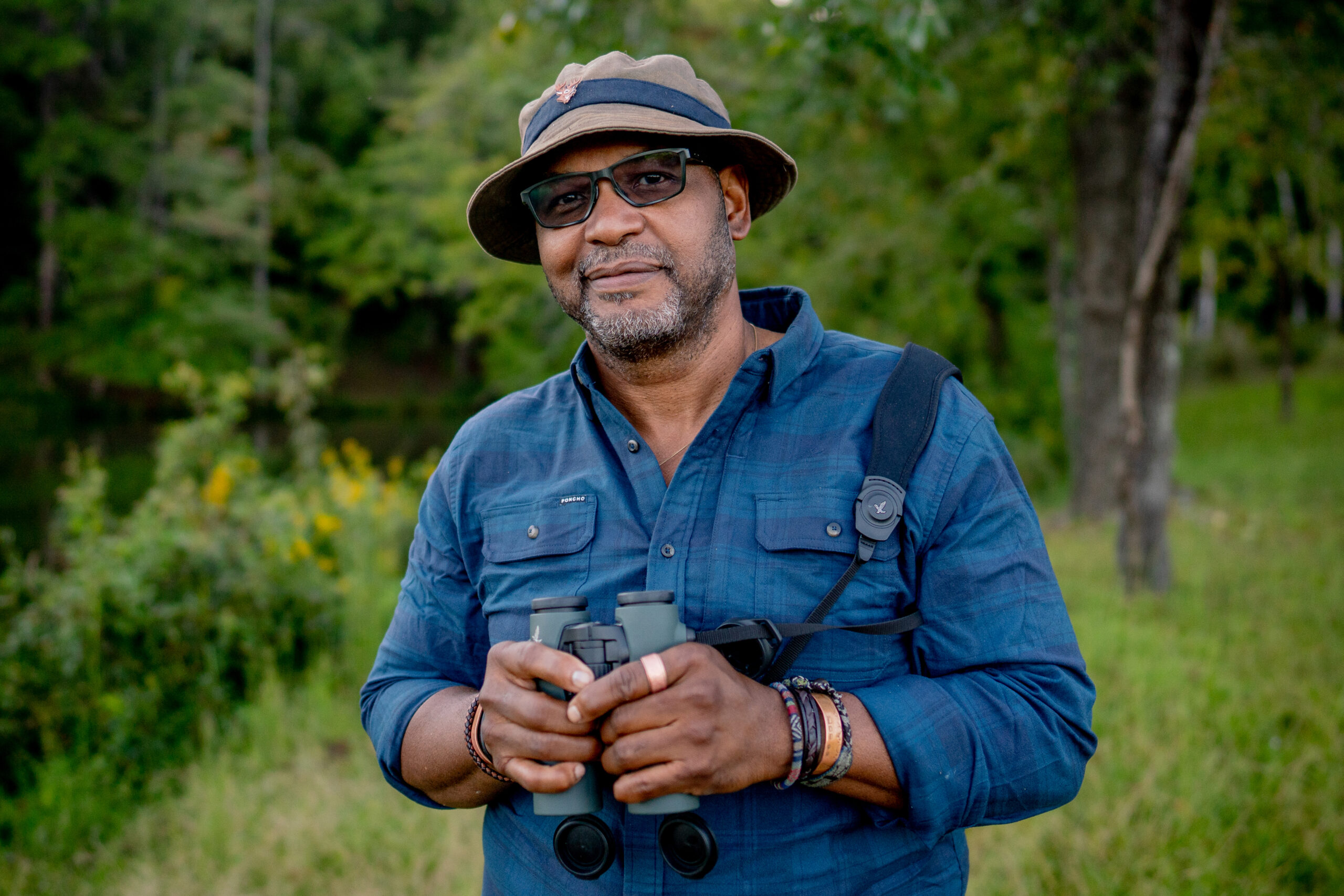 image: J. Drew Lanham poses for a photo with his binoculars.