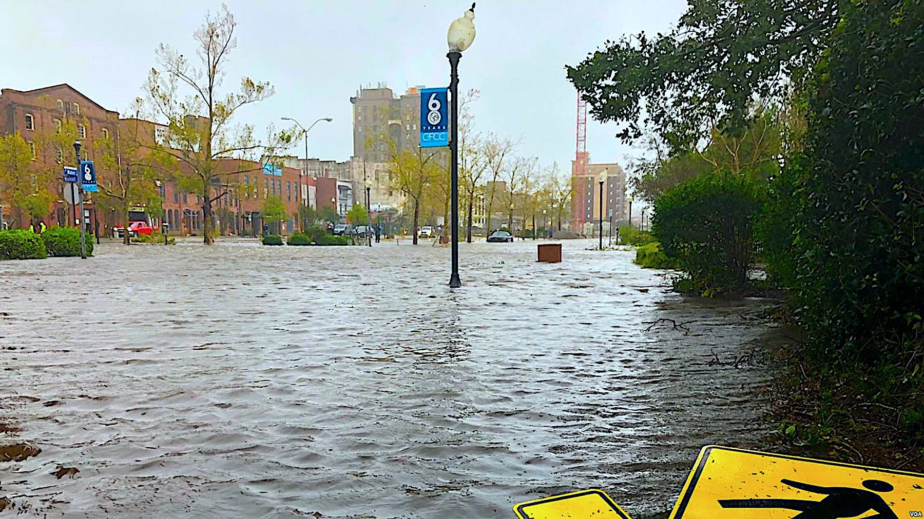 Flooded streets with a fallen pedestrian crossing sign.