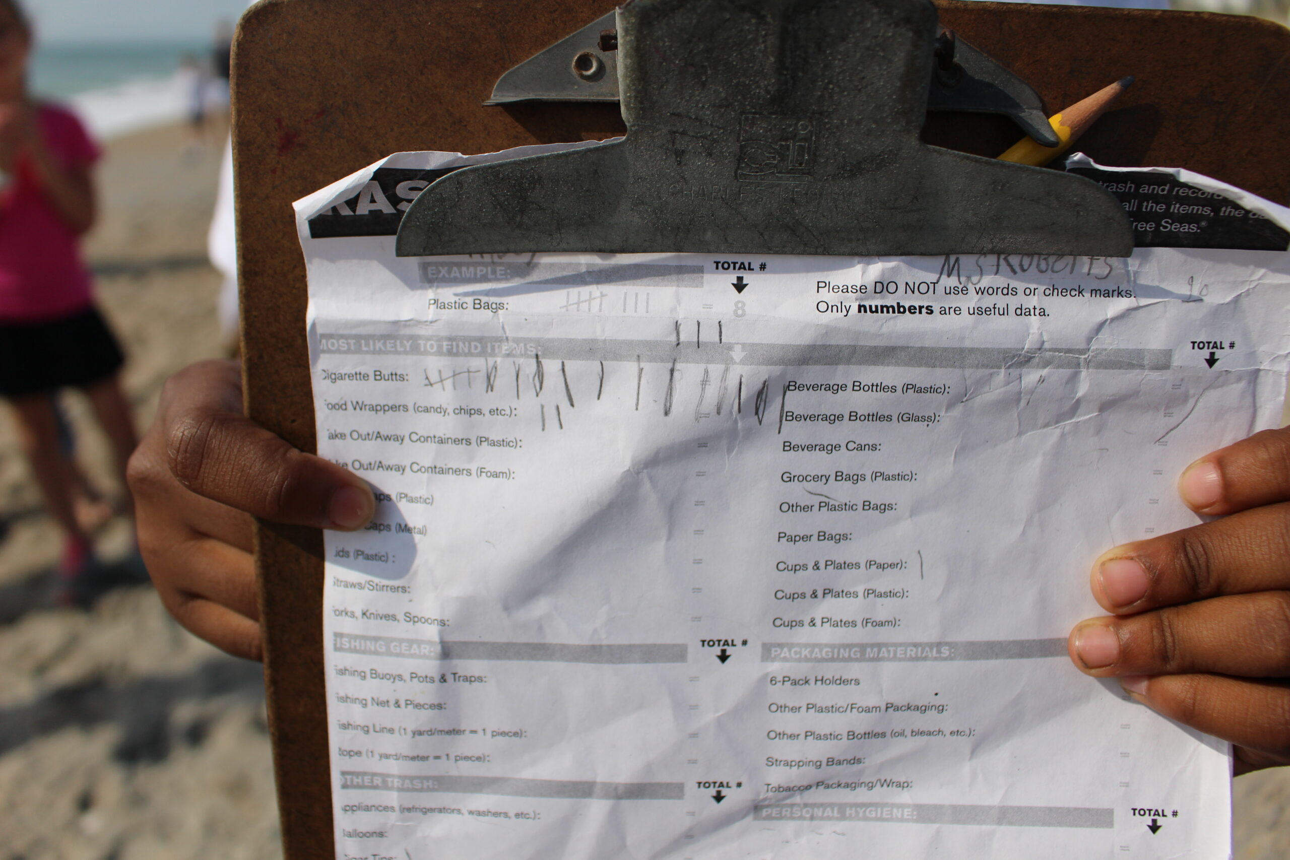 Child holds up a trash audit data sheet from a beach clean up.