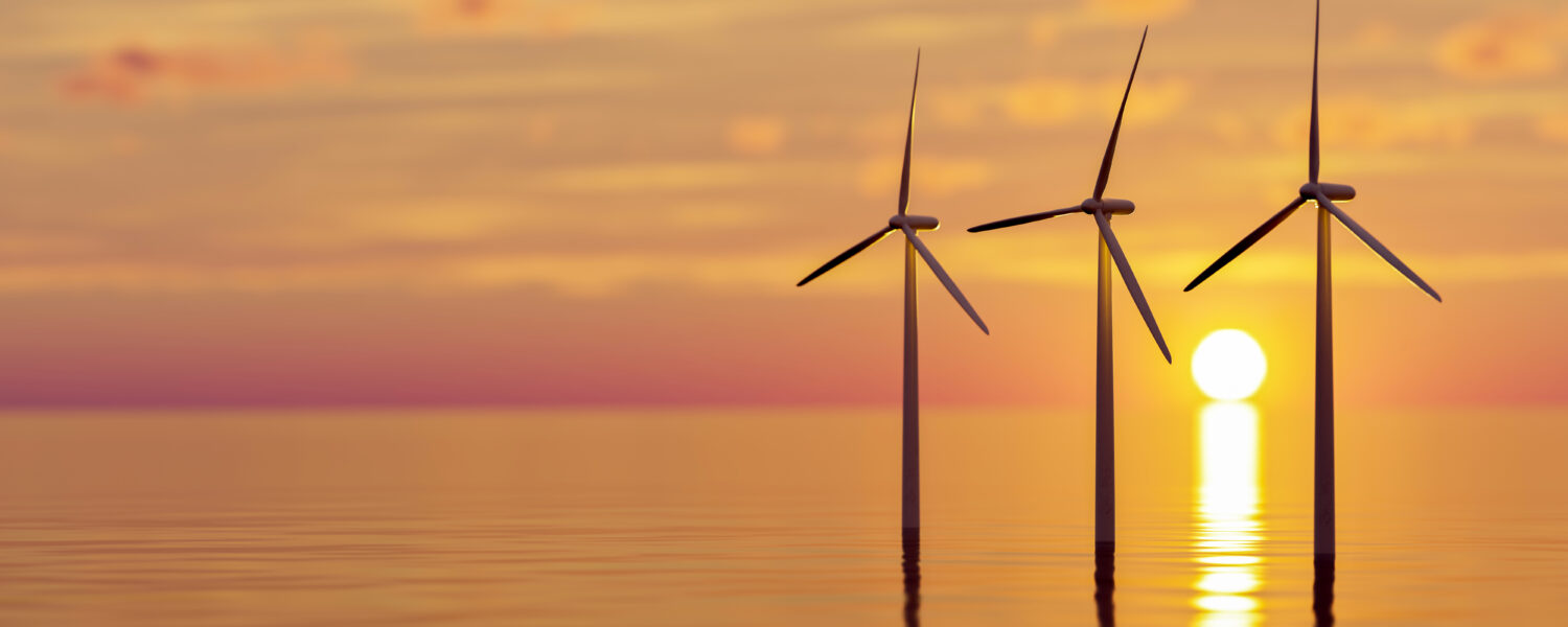 image: offshore wind turbines in front of a sunset.