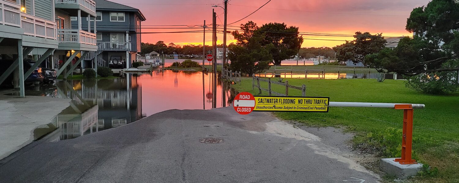 image: flooded residential street at sunset.
