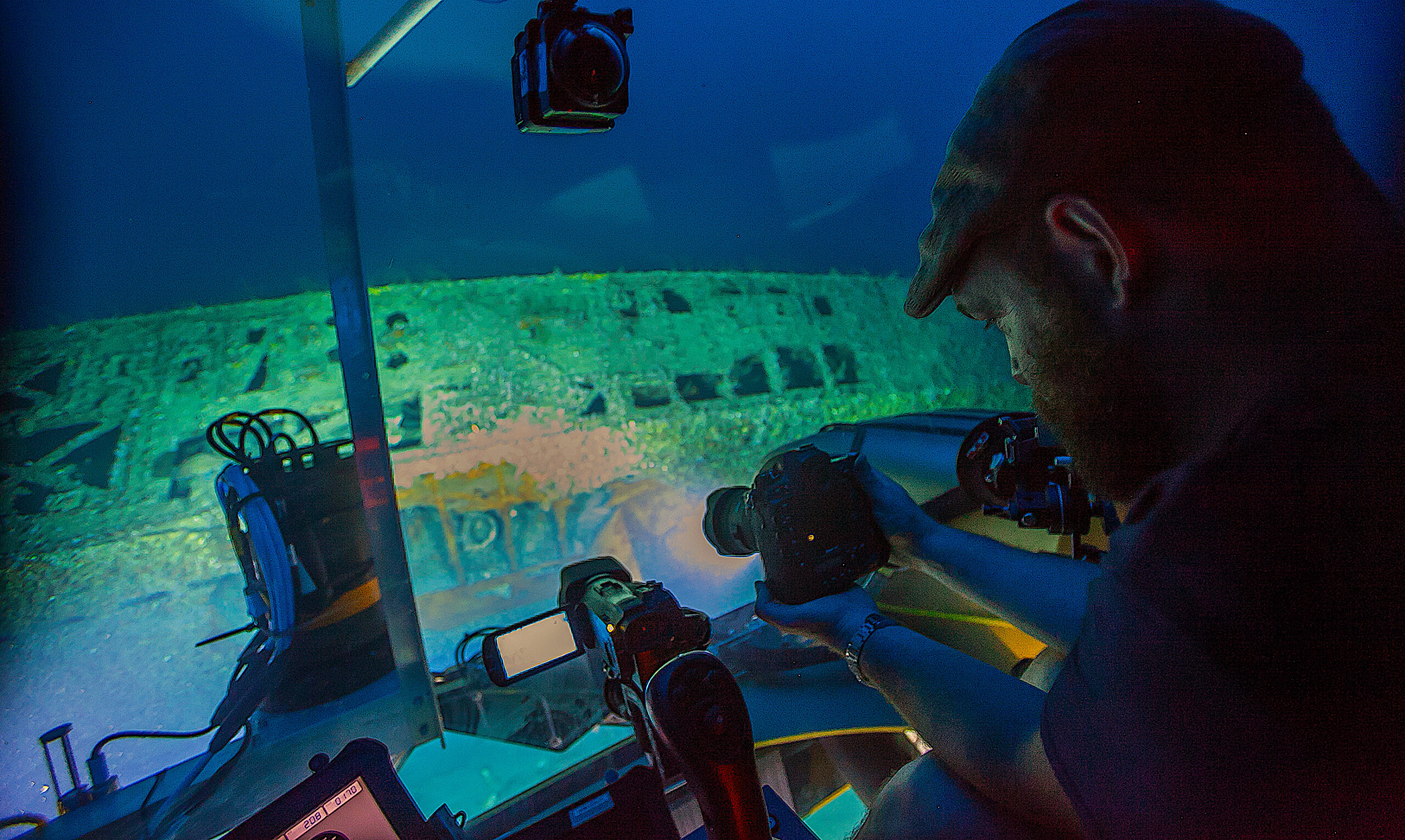 Joe Hoyt, Maritime Archaeologist with the NOAA Office of National Marine Sanctuaries, takes photos of the shipwreck from the submersible. Image courtesy of Carmichael, Project Baseline - Battle of the Atlantic expedition.