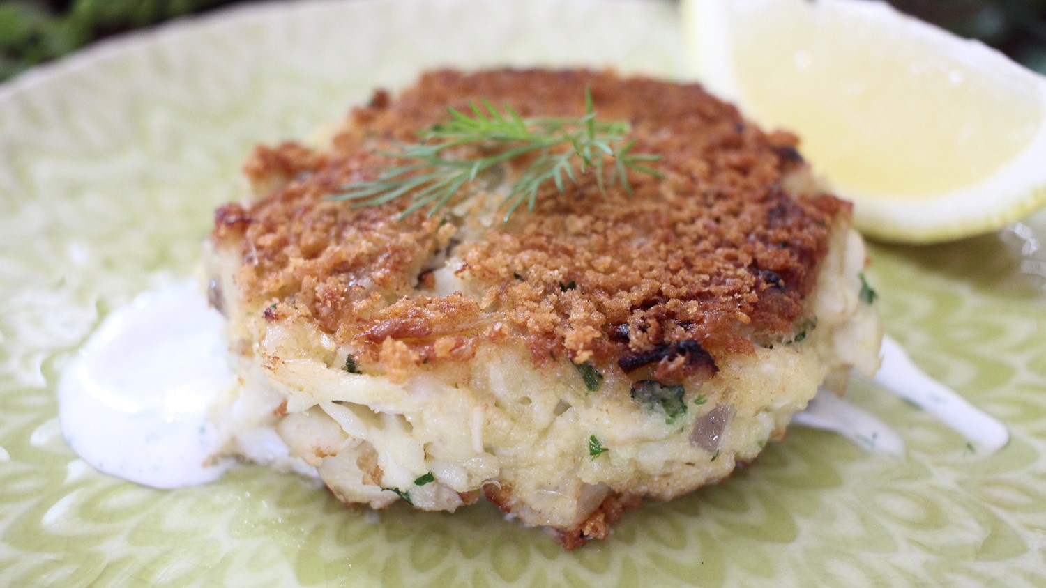 A crab cake with lemon-dill sauce