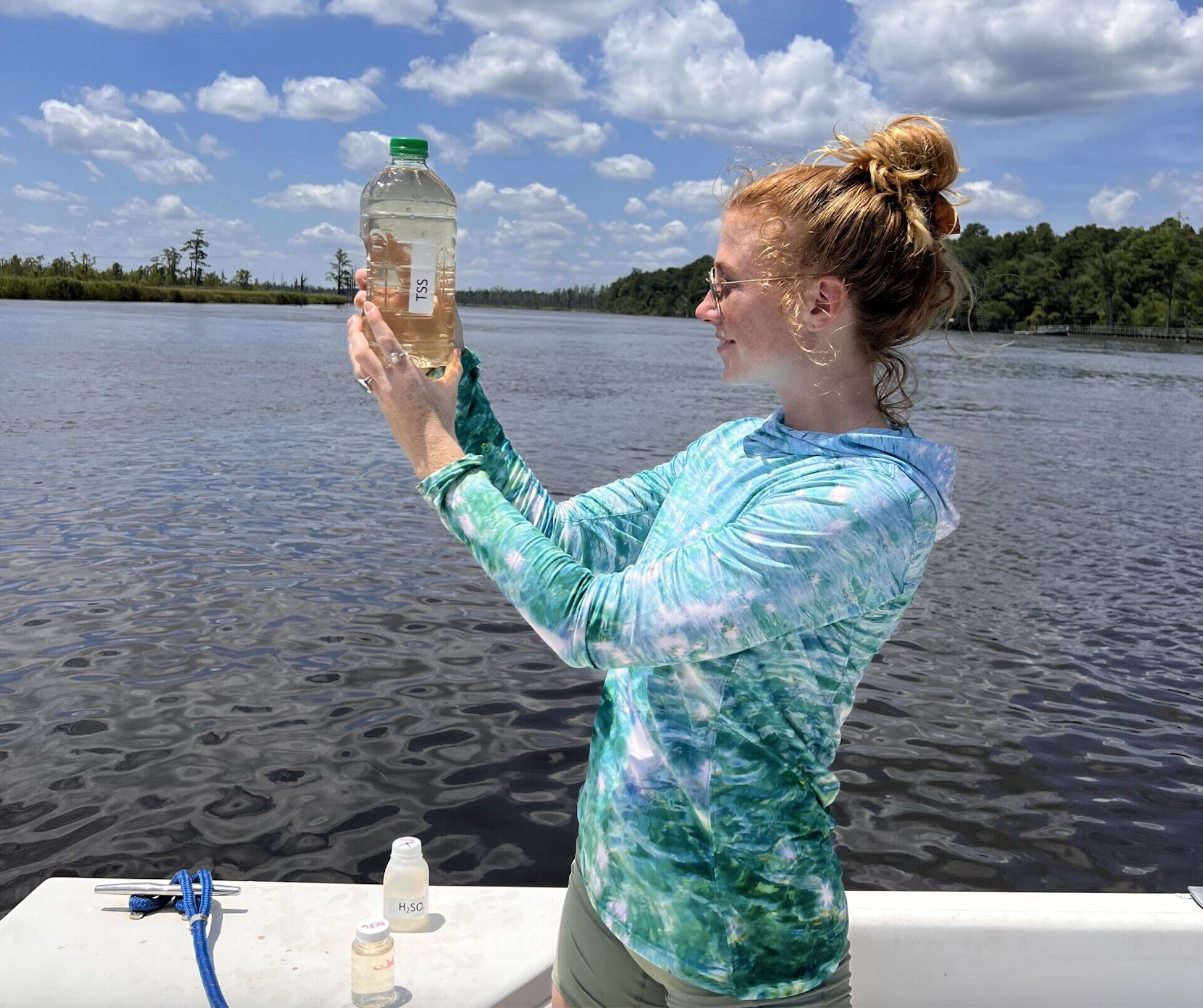 Colleen holds a bottle filled with sampled water while on a boat.