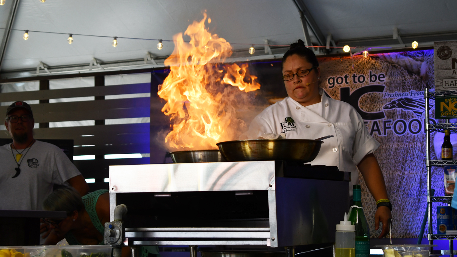 a chef cooks on stage at the North Carolina Seafood Festival. A big flame is emitting from her pan