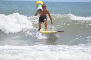 Man on surfboard retrieving drifter in ocean.