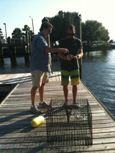 Two men with crab pot on pier.