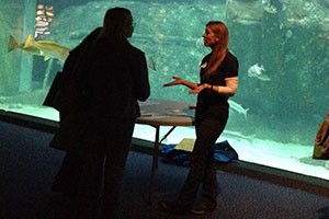 Jennifer talking to teachers in front of big fish tank