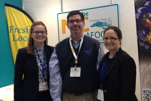 Three people in front of NC Seafood posters at Seafood Expo.