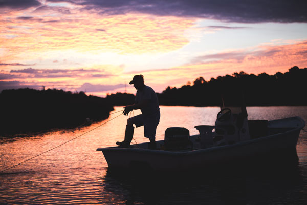 Sillhouette of fisherman on boat pulling a net