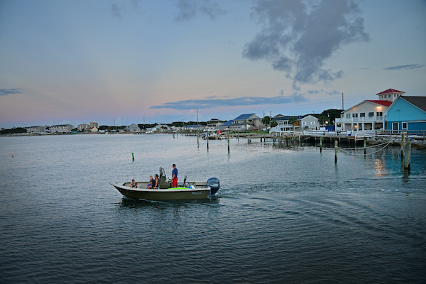 Family in small boat on the water with buildings in the background