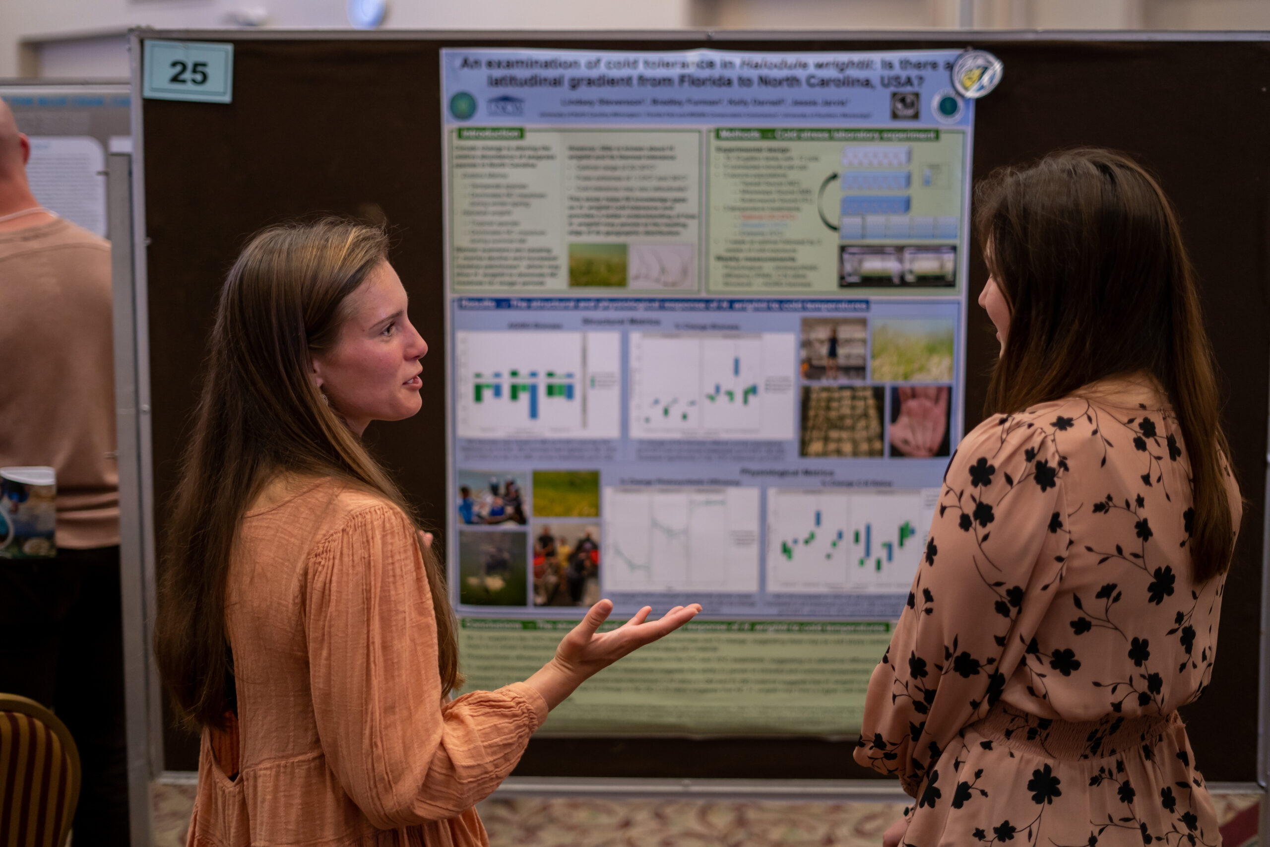 Lindsey Stevenson talking to a woman about her research while standing in front of her poster