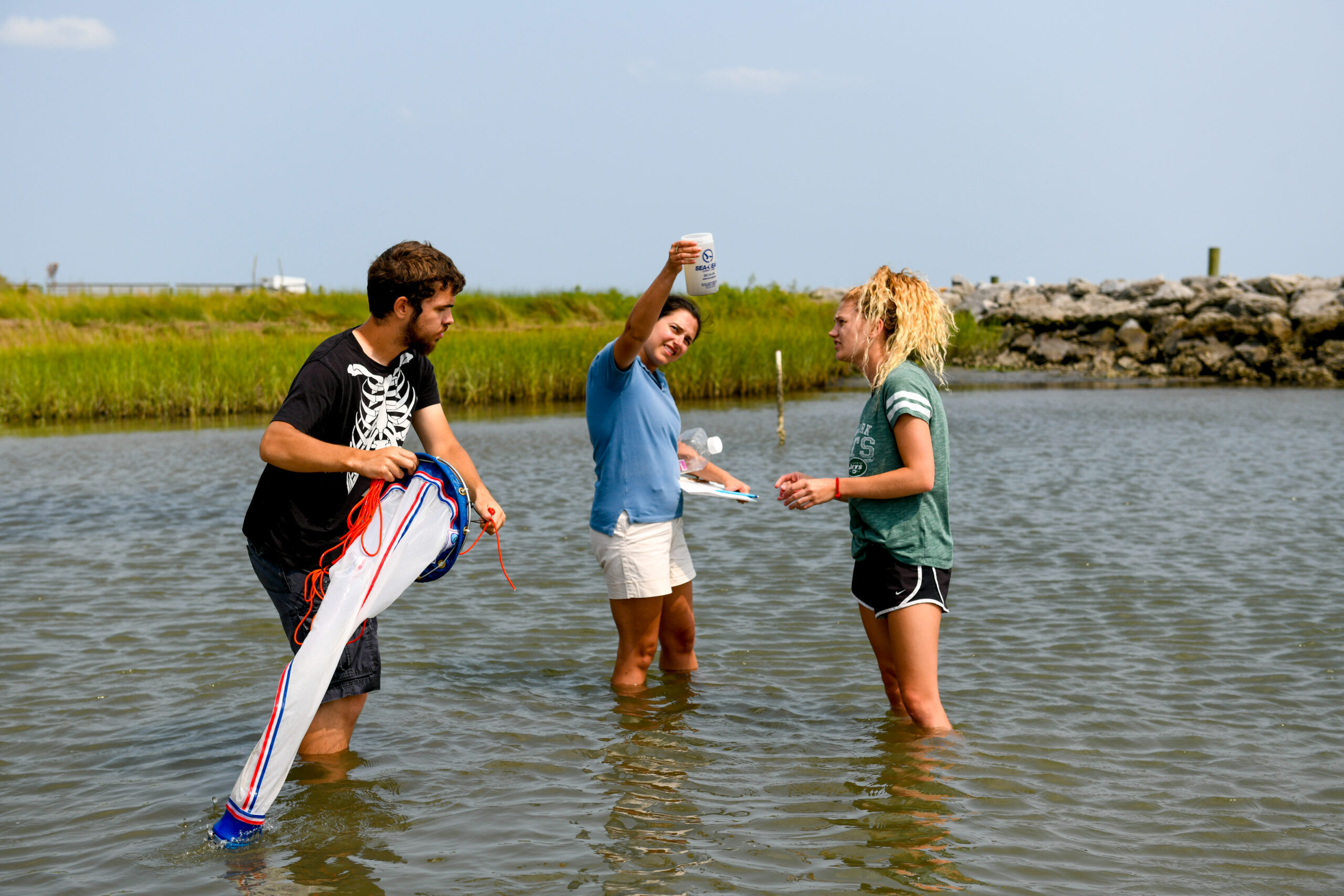 Three people collect and look at water samples from the ocean.