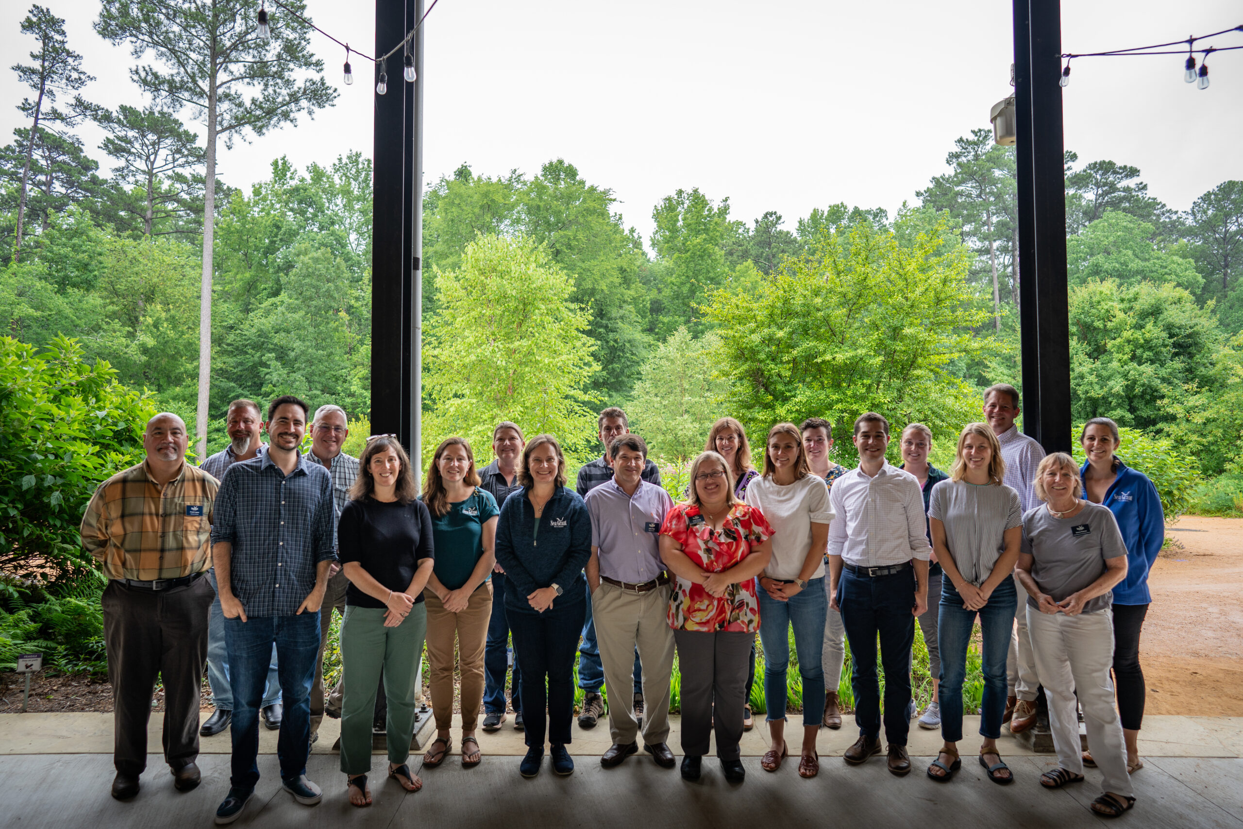 group photo of our advisory board and staff at the 2023 meeting standing in front of trees