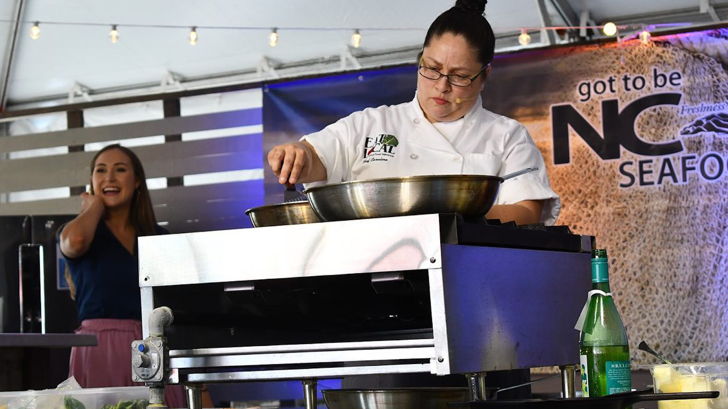 a chef cooking with a skillet on stage at the NC Seafood Festival