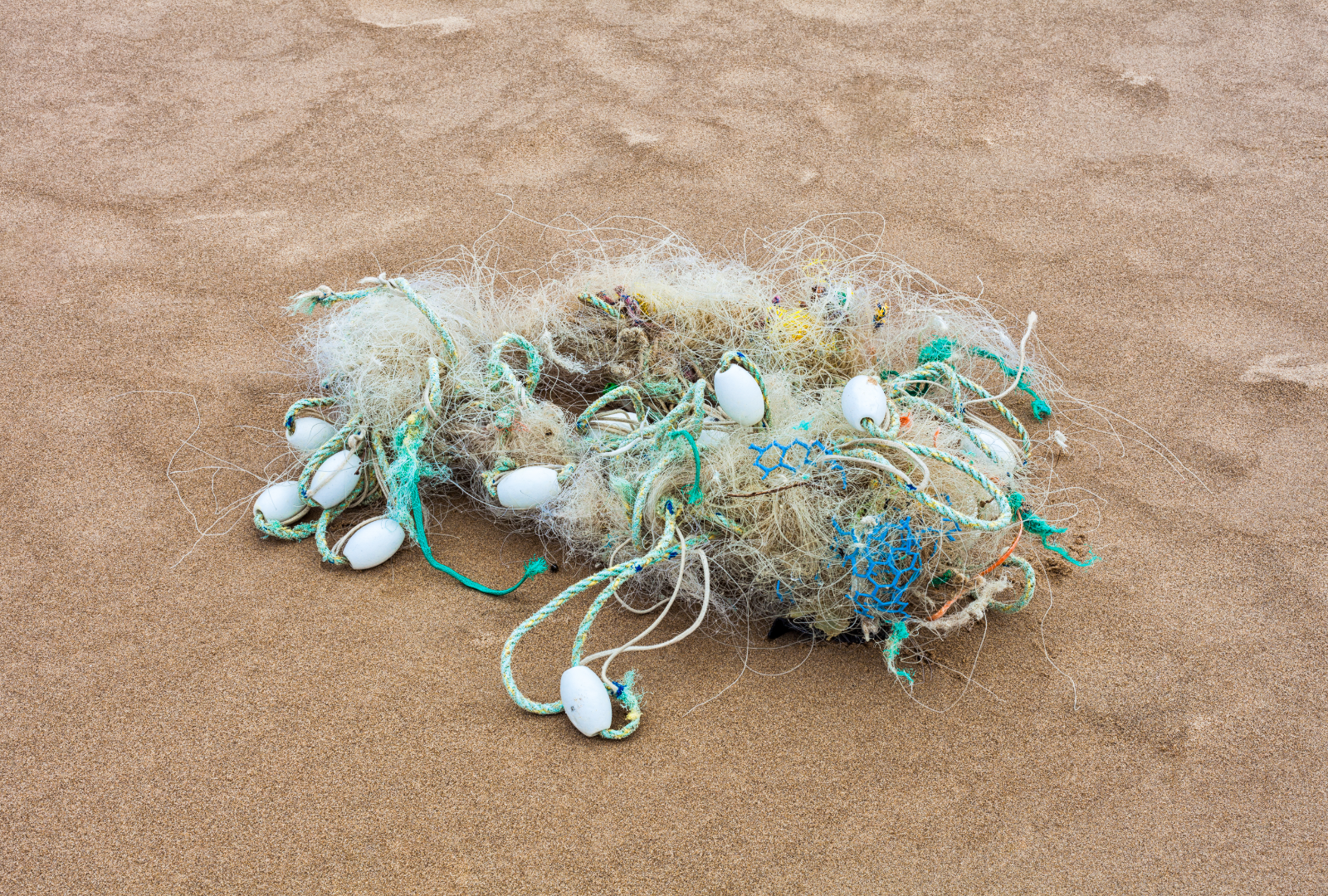 old fishing nets and other marine debris washed up on a sandy beach