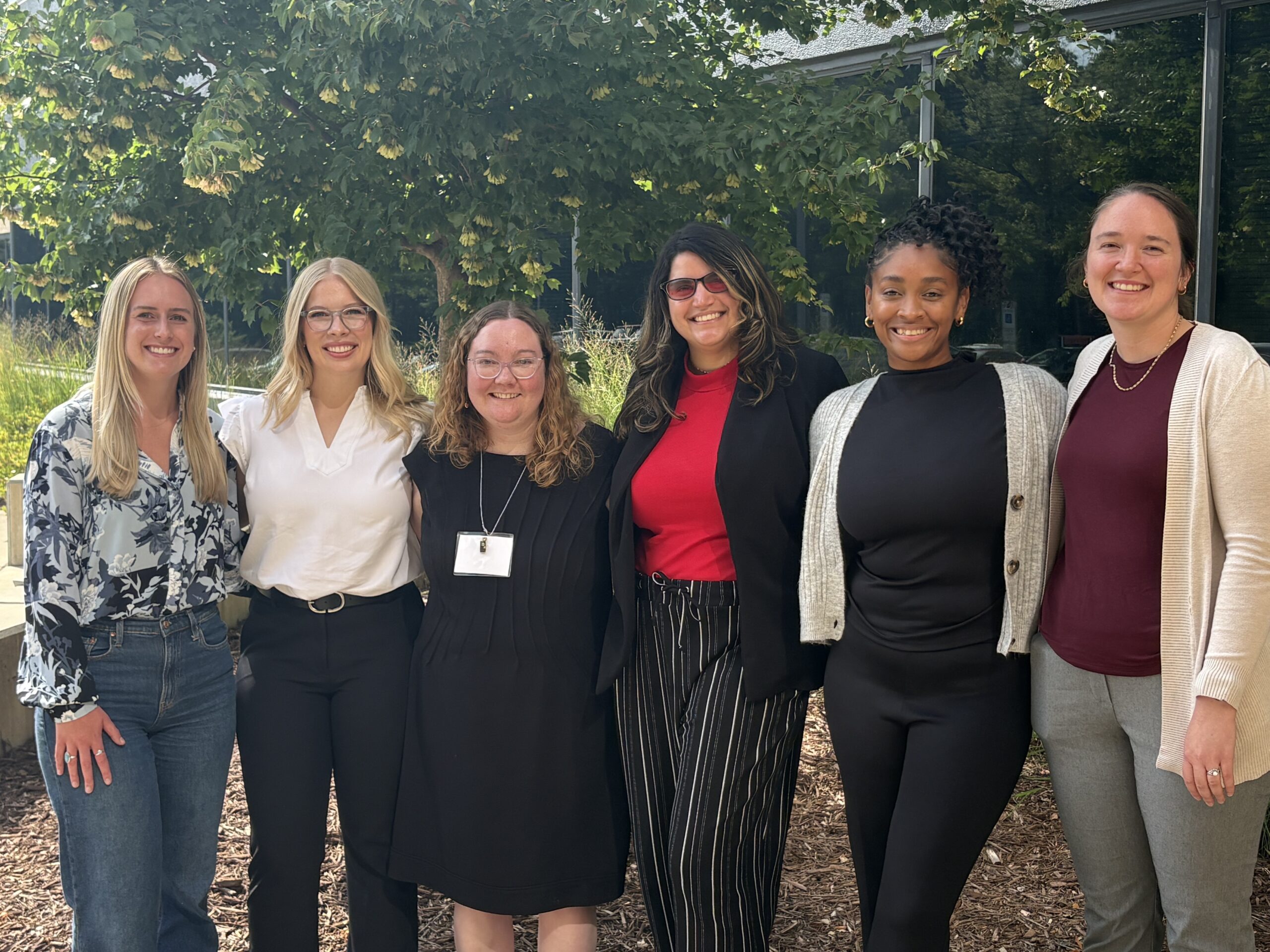 Six women standing side by side outdoors