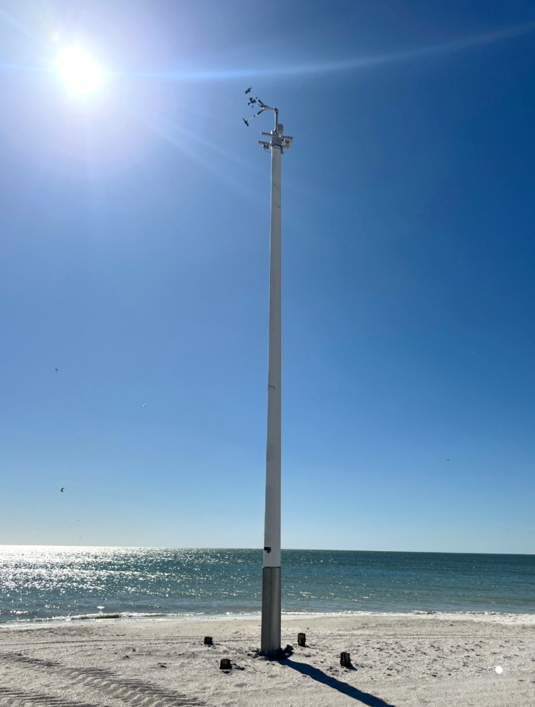 A sentinel tower on a beach with the ocean behind.